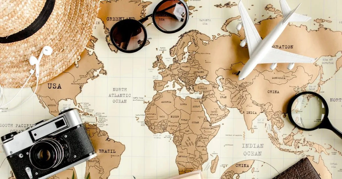 Homeopathic Remedies for Motion Sickness, Jet Lag and Travel Stress World map with a toy airplane, camera, sunglasses and sun hat