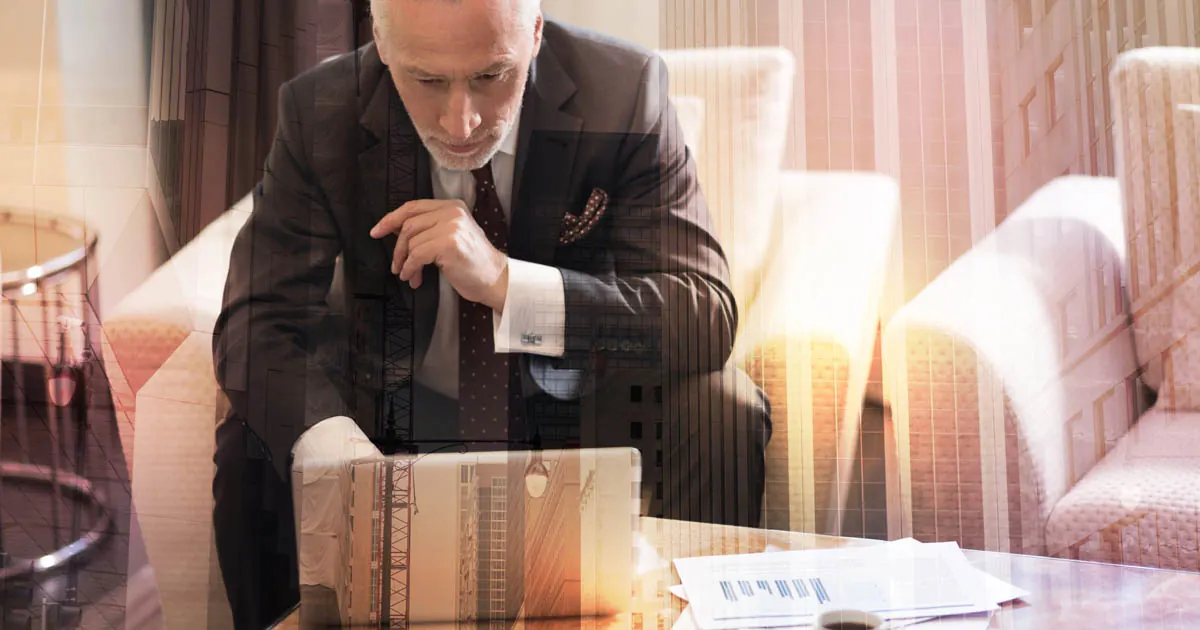 Tired older man rubbing his eyes at a desk