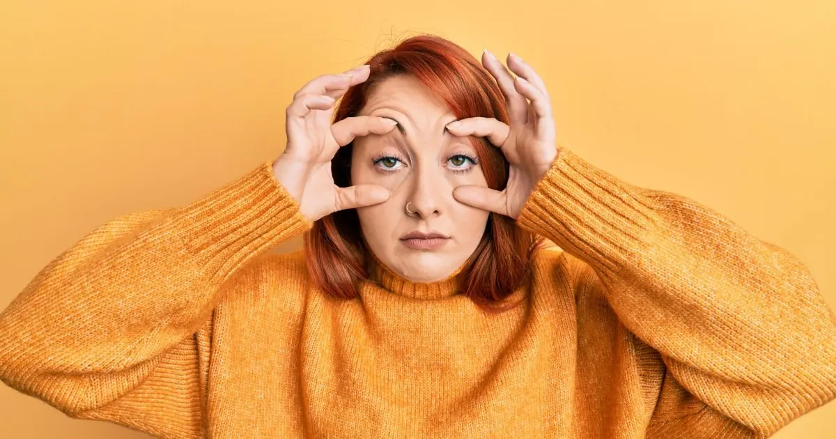 woman trying to open eyes with fingers