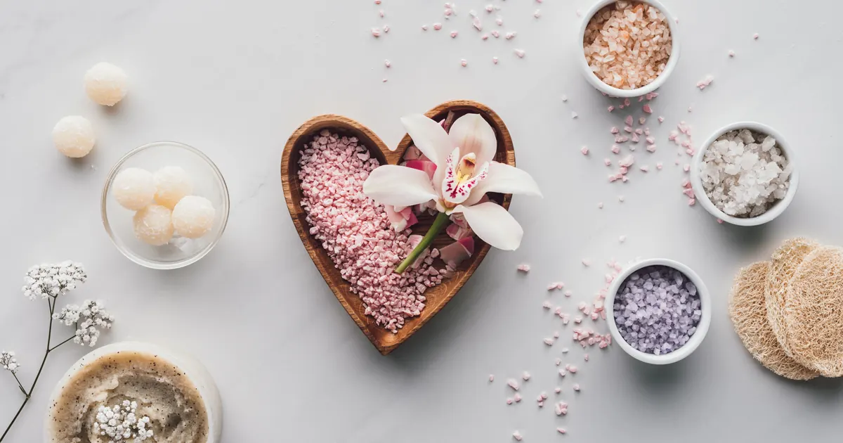 Heart-shaped bowl of bath salts with an orchid and spa items