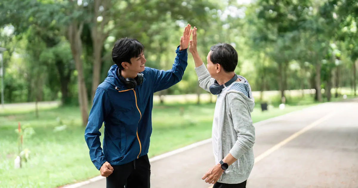 Two friends giving a high five while out for a walk in the park